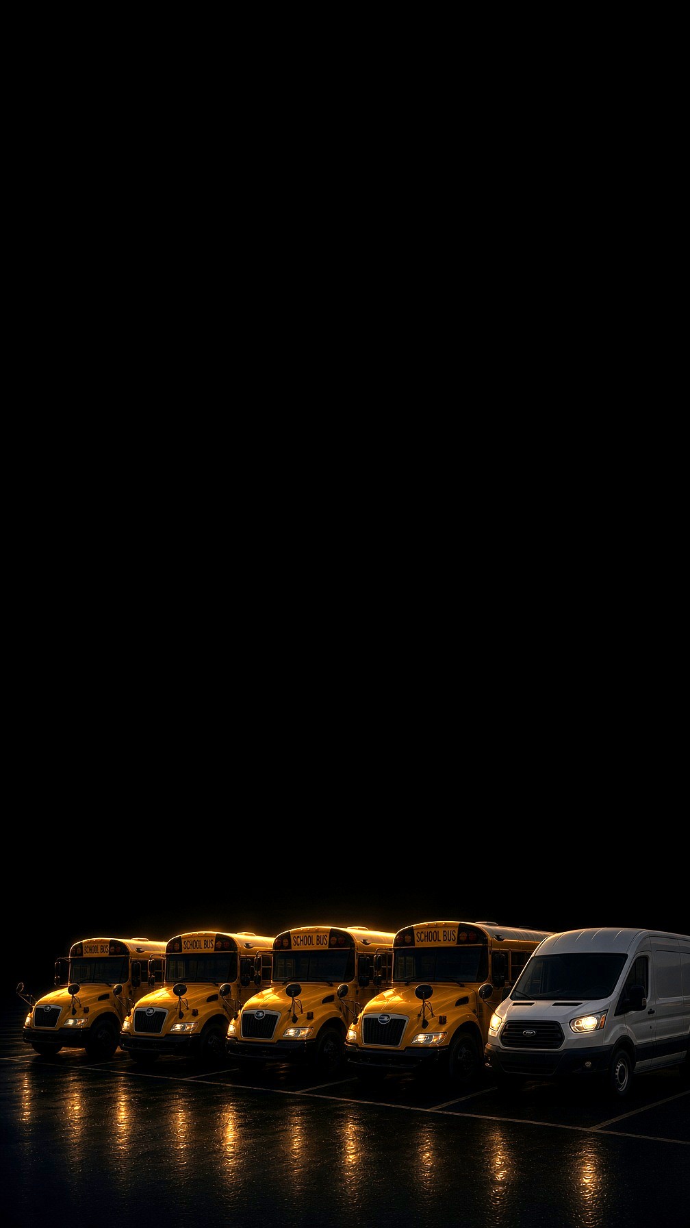 School buses and a commercial van parked together at night